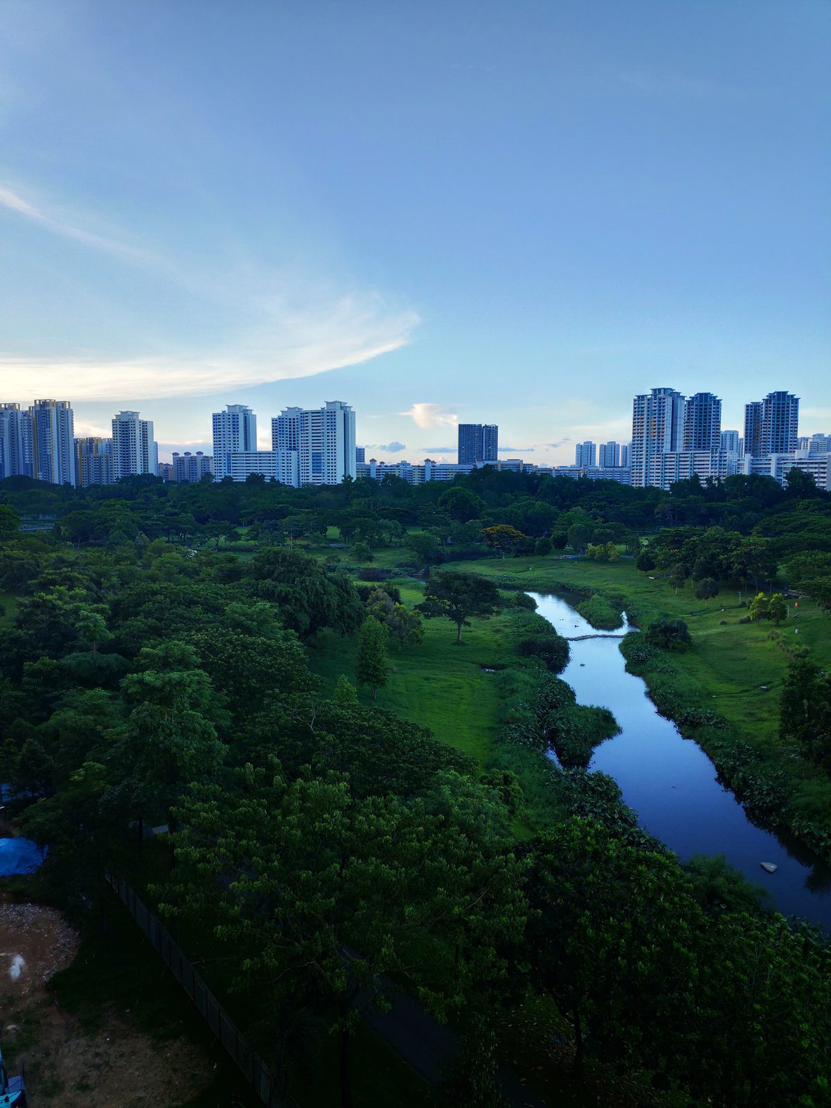 A green corridor and canal with the Singapore skyline behind, Bishan Park