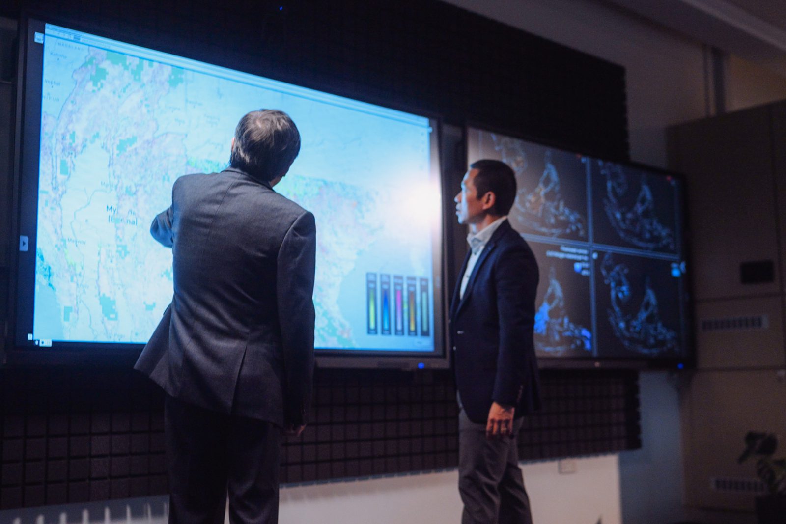 Two people at the Decision Theatre display wall, one pointing at a map of Southeast Asia